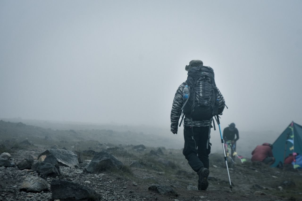 A hiker with gear treks through a foggy mountain landscape in Jawa Barat, Indonesia.